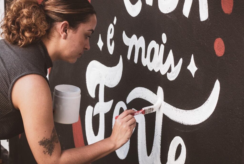 artista pintando lettering em mural